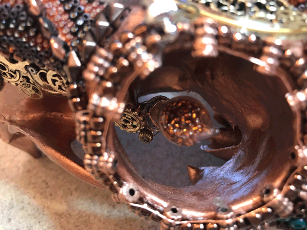 A close up view of Grand Chaos, a whitetail buck beaded skull Steampunk deer art piece mechanical glass eye.